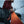 Person in red jacket holding orange climbing skin for skis next to a truck in the snow