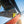 Skier in mid air wearing yellow ski boots and grey pants against a blue sky