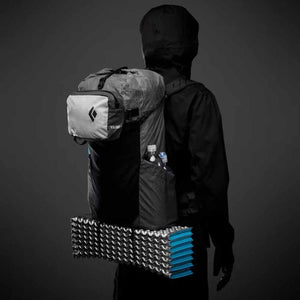 Person wearing a Black Diamond Beta Light backpack with a foam sleeping pad attached to the bottom