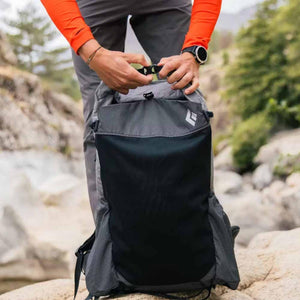 Person fastening the buckle on a Black Diamond backpack outdoors