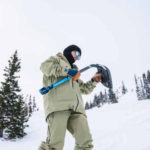 Person in winter gear holding a Black Diamond snow shovel in a snowy landscape