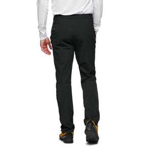 Back view of Black Diamond black technical trousers on a person wearing a white long sleeve shirt and hiking shoes