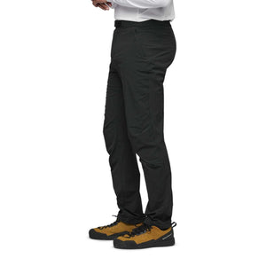 Side view of Black Diamond black technical trousers worn with brown approach shoes