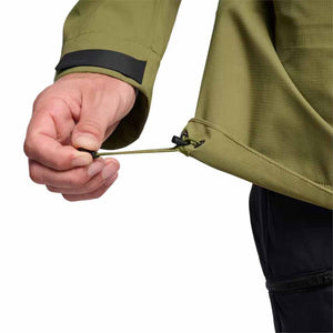 Hand adjusting the hem drawcord on a Black Diamond olive green jacket