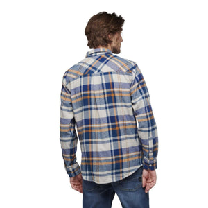Back view of a man wearing a blue and tan plaid long sleeve flannel shirt