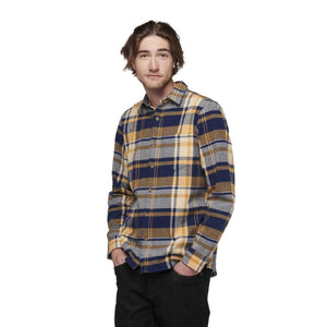 Man wearing a Black Diamond blue and yellow plaid long sleeve button down shirt
