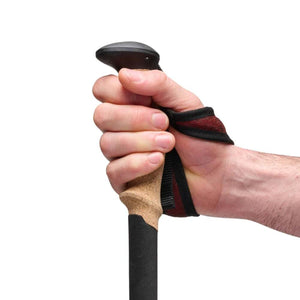 Hand gripping a trekking pole with a cork handle and red strap