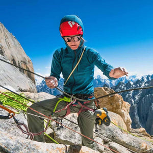 Climber wearing a Black Diamond helmet and jacket handling climbing ropes on a mountain ridge