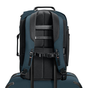 Back view of blue Briggs and Riley backpack with padded shoulder straps attached to luggage handle