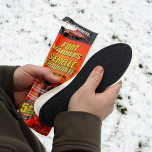Hands holding a Grabber foot warmer insole package against a snowy background