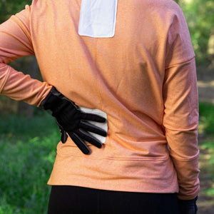 Person wearing Hothands heat packs on lower back and neck under an orange long sleeve shirt