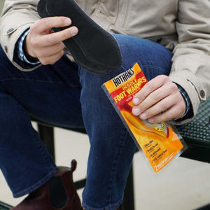 Person holding Hothands insole foot warmers package and black insole