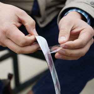 Hands peeling the protective film off a Hothands adhesive warmer