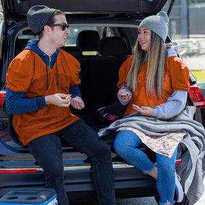 Two people wearing orange Hothands jerseys sitting in the back of a car