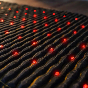 Close up of red LED lights embedded in a textured black fabric surface