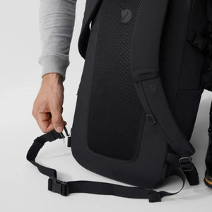 Person adjusting the chest strap on a black Fjallraven backpack
