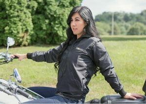 Woman wearing a black California Heat jacket while sitting on a motorcycle