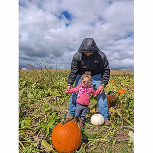 Adult wearing California Heat jacket holding childs hands in a pumpkin patch