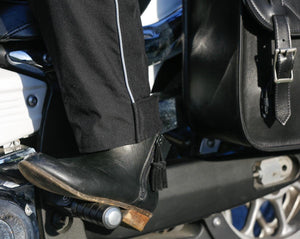 Black leather motorcycle boot resting on a foot peg
