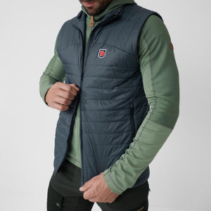 Man wearing a dark blue FjallRaven quilted vest over a green long sleeve shirt