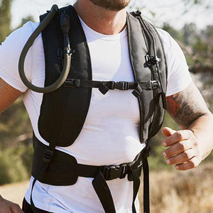 Person wearing a black hydration vest with a drinking tube over a white t-shirt