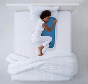 Person sleeping on a Cool Care Technologies blue cooling pad on a white bed