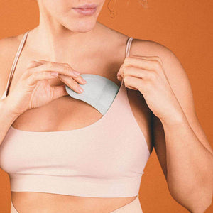 Person placing an Opal Cool cooling pad inside a sports bra