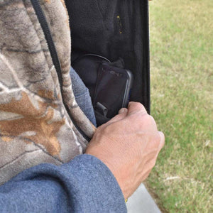 Hand placing a smartphone into the internal pocket of a DeWalt camouflage jacket