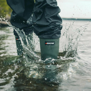 Person wearing green Baffin rubber boots splashing in shallow water