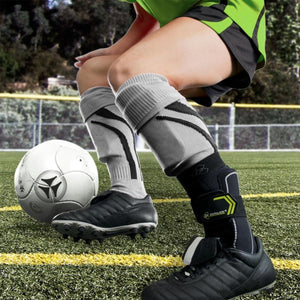 Soccer player wearing a black DonJoy ankle brace over a sock on a field