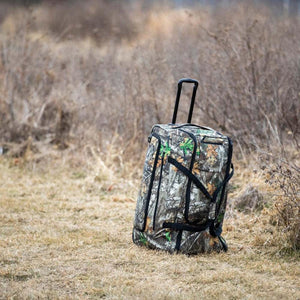 DSG Outerwear camo rolling gear bag standing in a field