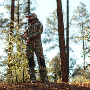 Person wearing DSG Outerwear camouflage hunting jacket and pants in a forest
