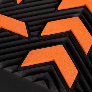 Close up of black rubber shoe sole with orange chevron tread pattern