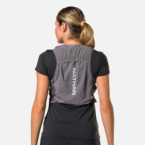 Back view of a person wearing a grey Nathan hydration vest over a black t-shirt