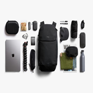 Bellroy backpack surrounded by organized travel accessories and electronics on a white background