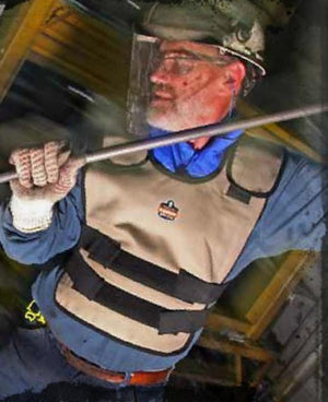 Worker wearing a tan protective vest and face shield holding a metal rod