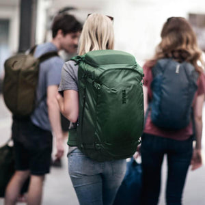 Three people walking outdoors wearing Thule backpacks