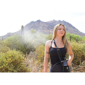 Woman using an ExtremeMIST personal cooling system in a desert landscape