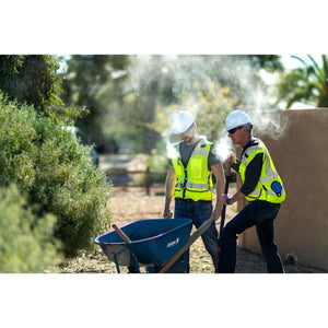 Two construction workers wearing ExtremeMIST cooling vests and hard hats while working outdoors
