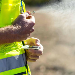 ExtremeMIST cooling system nozzle spraying a fine mist while held by a person in a high visibility vest