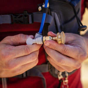 Hands connecting ExtremeMIST brass nozzle to blue hydration tube