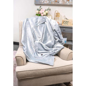 Light blue ThermalStep heated throw blanket draped over a beige armchair