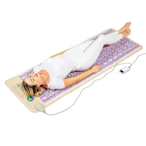Person lying on a HealthyLine infrared heating mat with embedded crystals and a handheld controller