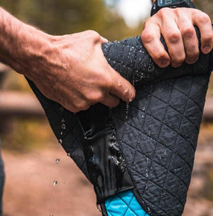 Mobile Cooling quilted fabric being wrung out with water droplets falling