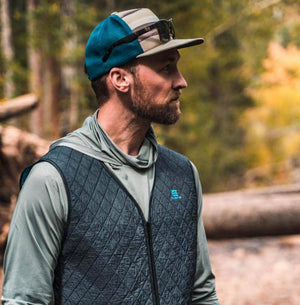 Man wearing a Mobile Cooling quilted vest and cap in a forest setting