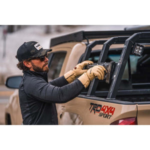 Man wearing Mobile Warming tan leather gloves adjusting gear on a truck bed rack