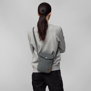 Person wearing a grey FjallRaven crossbody bag over a grey sweatshirt
