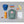 Fjallraven Kanken backpack with blue cap, Primus bottle, markers, notebook, apple, banana, and nuts on grey background