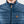 Close up of blue FjallRaven quilted vest with leather zipper pull and fox logo patch