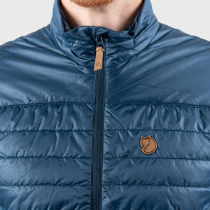 Close up of blue FjallRaven quilted vest with leather zipper pull and fox logo patch